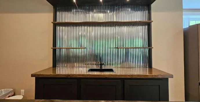 Back bar with corrugated metal wall, floating shelves, lights and a black sink